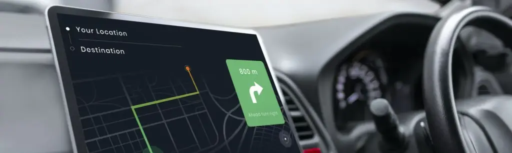 Bild eines Autocockpits mit einem Bildschirm auf dem eine Navigationssoftware abgebildet ist.